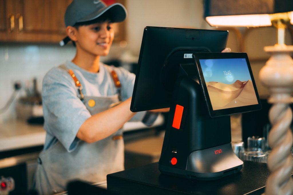 Commerçante réglant l'écran double d'un logiciel de caisse posé sur un comptoir